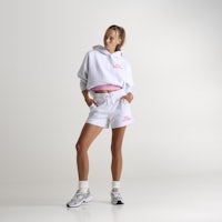 a woman wearing a white hoodie and pink shorts