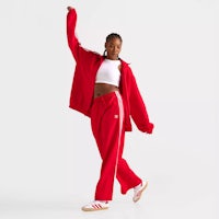 a woman wearing red track pants and a white tee