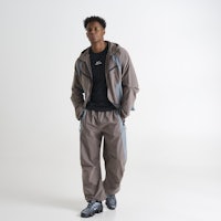 a man in a grey tracksuit standing in front of a white background