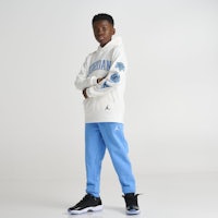 a young boy wearing a white sweatshirt and blue sweatpants
