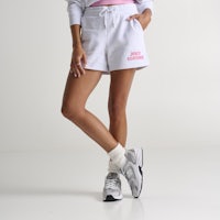 a woman wearing a grey sweatshirt and pink shorts